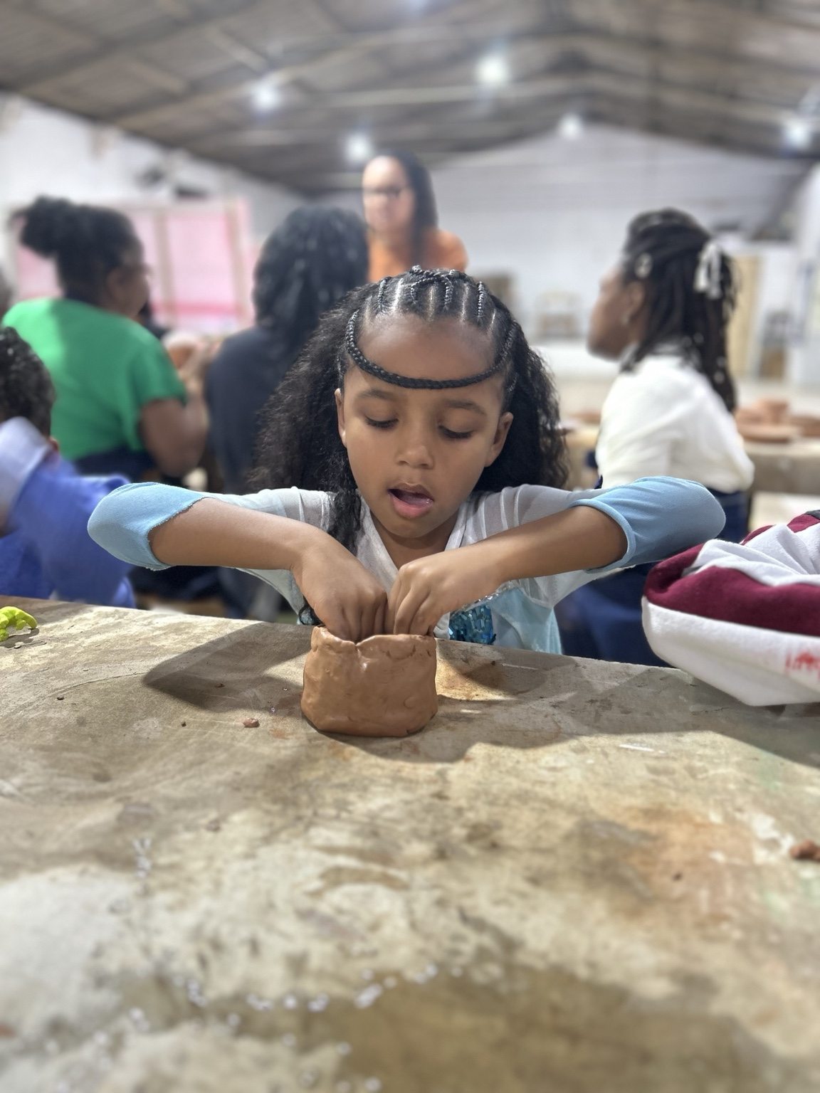 Criança modelando uma peça de barro